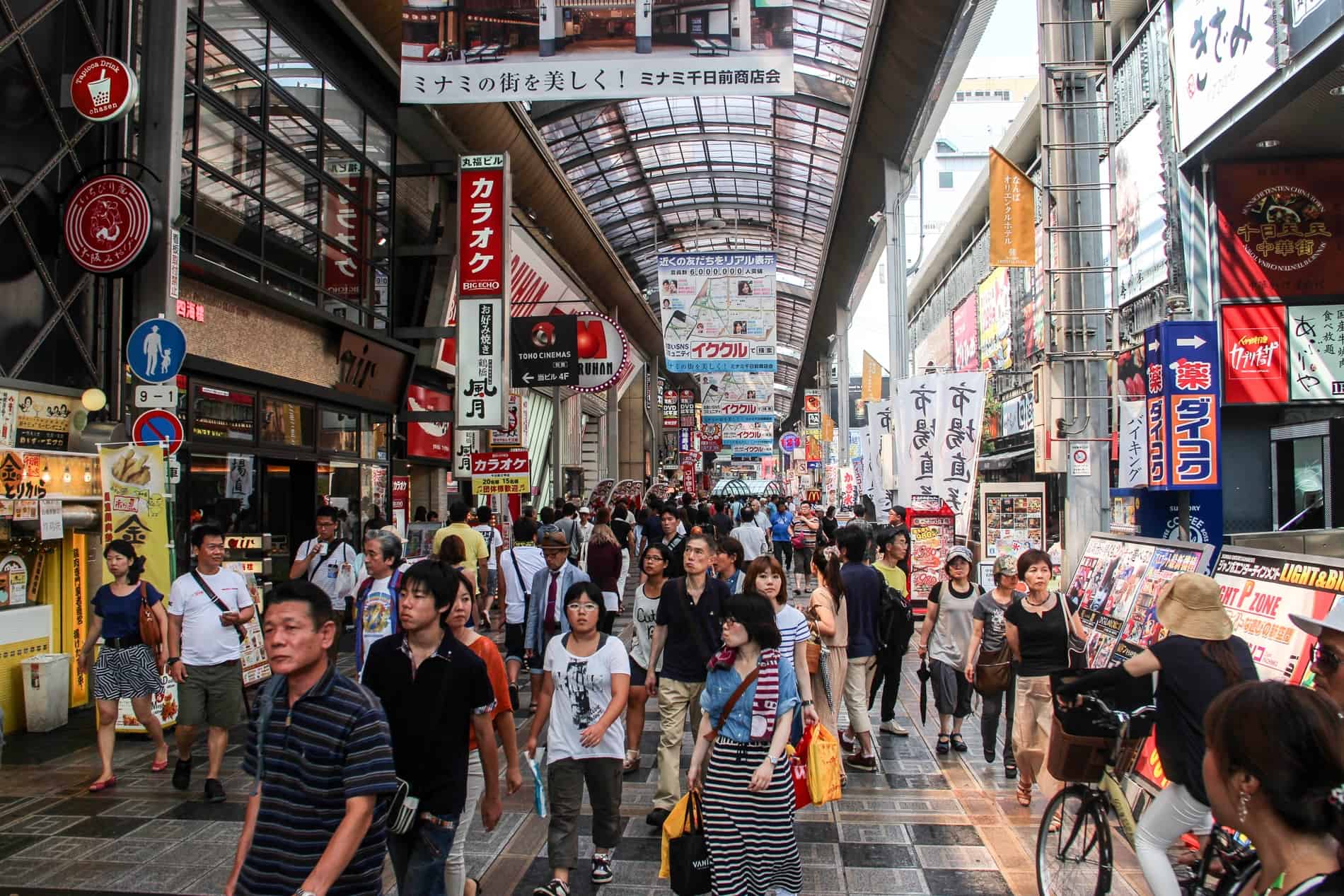 Japanese locals visiting a long and wide Ebisu Bashi Suji shopping arcade in Oska, packed with stores. 