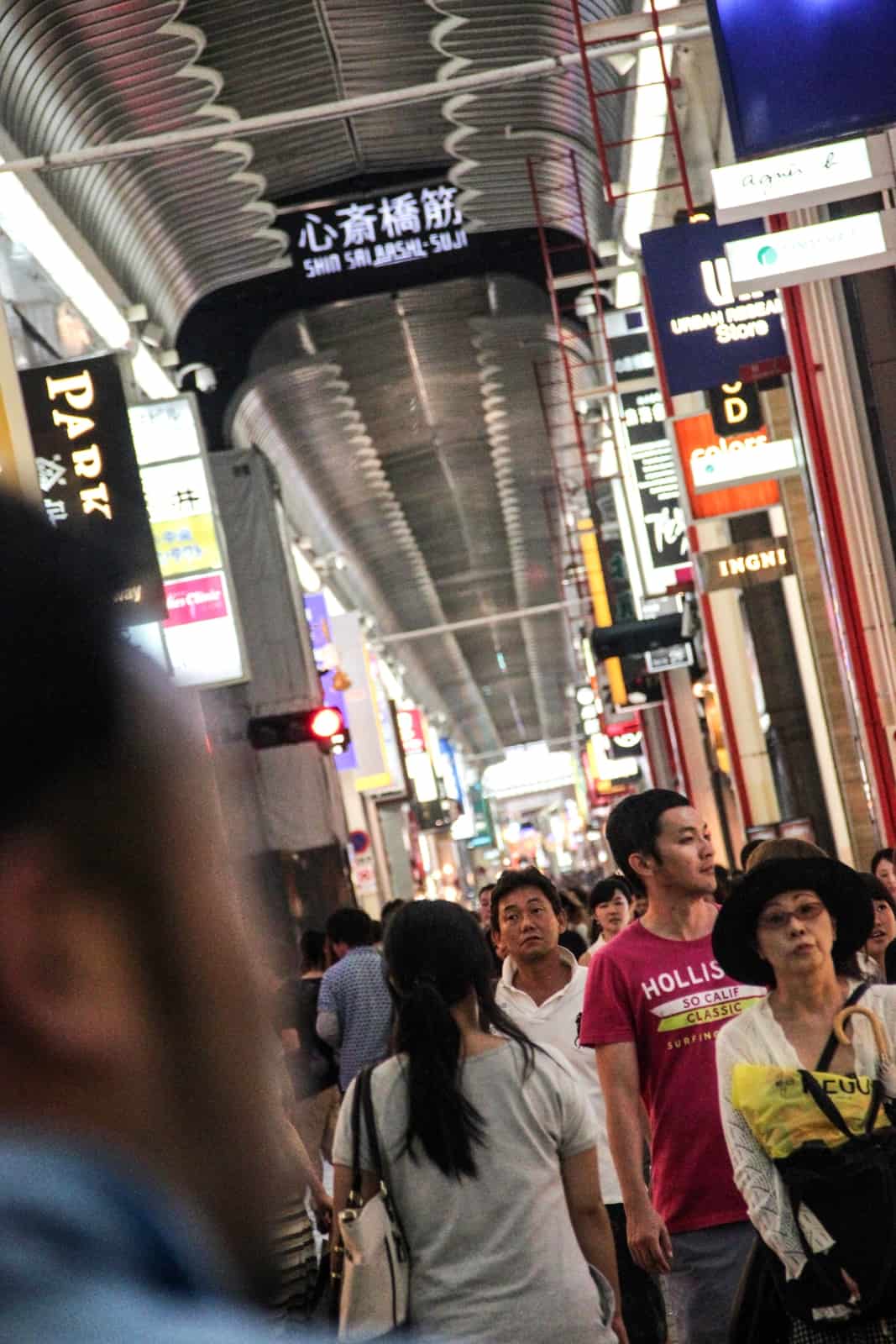 Japanese locals walking down the long narrow shopping arcade of Shinsaibashi Suji in Osaka. 