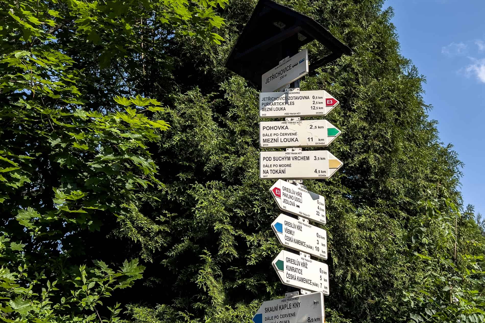A signpost showing the Red, Yellow, Green and Blue hiking trails in Bohemian Switzerland, Czech Republic.