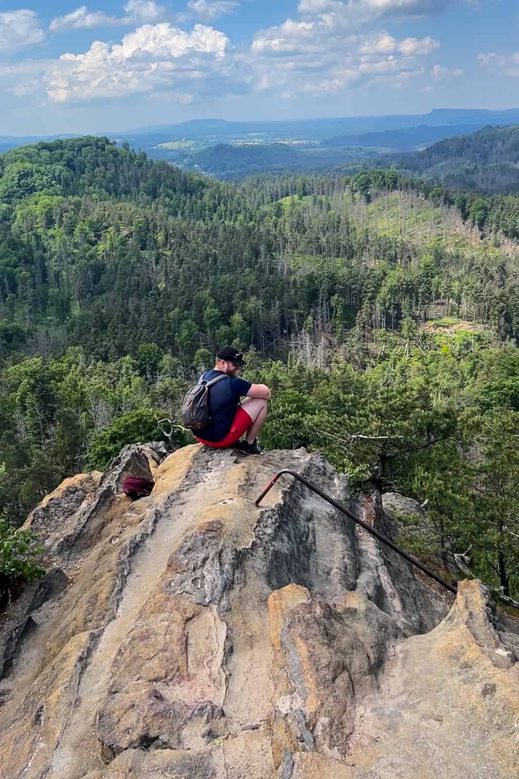 A man sits upon the spike rock summit of Rudolf’s Rock in Bohemian Switzerland. 