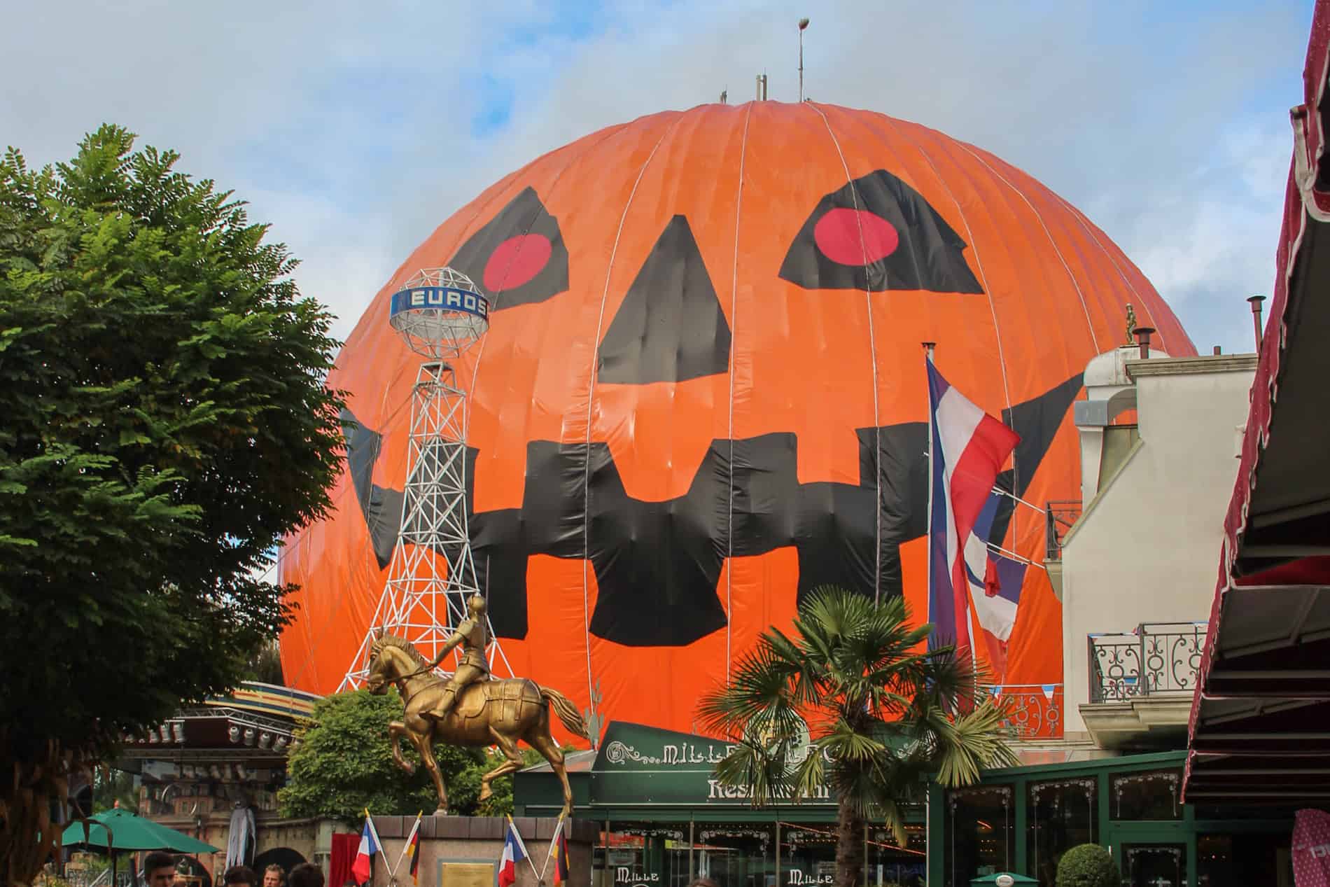 People walking in front of a giant pumpkin tent in Europa Park theme park in Germany. 