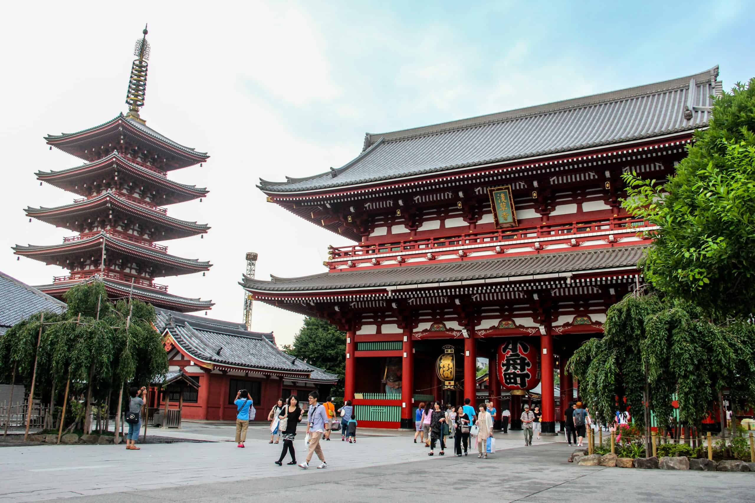 A Traditional red, multi-tiered Japanese temple in modern Tokyo.
