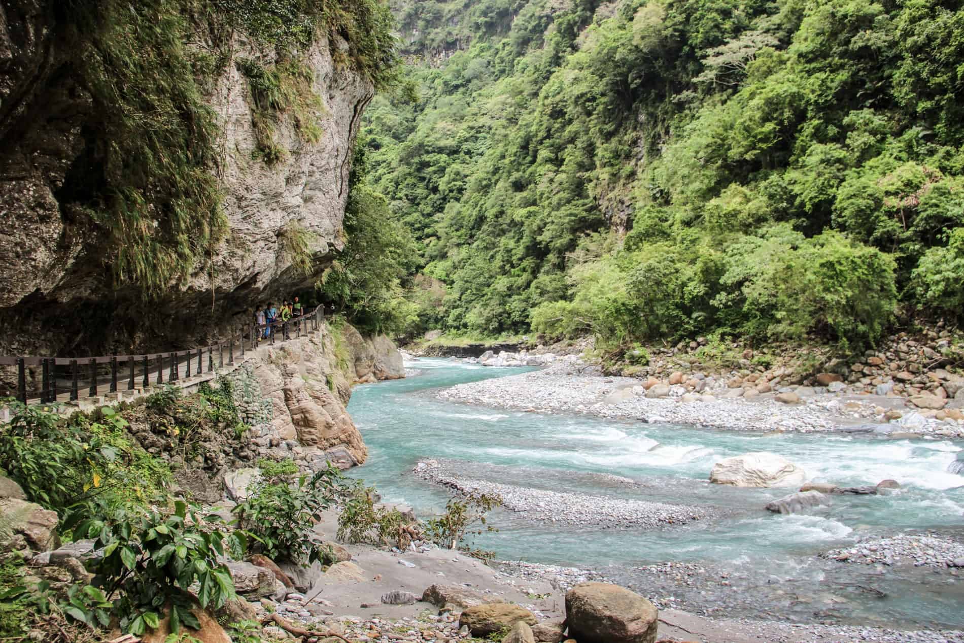 A walking trail cut into a cliff face next to the crystal blue waters of Taroko Gorge.