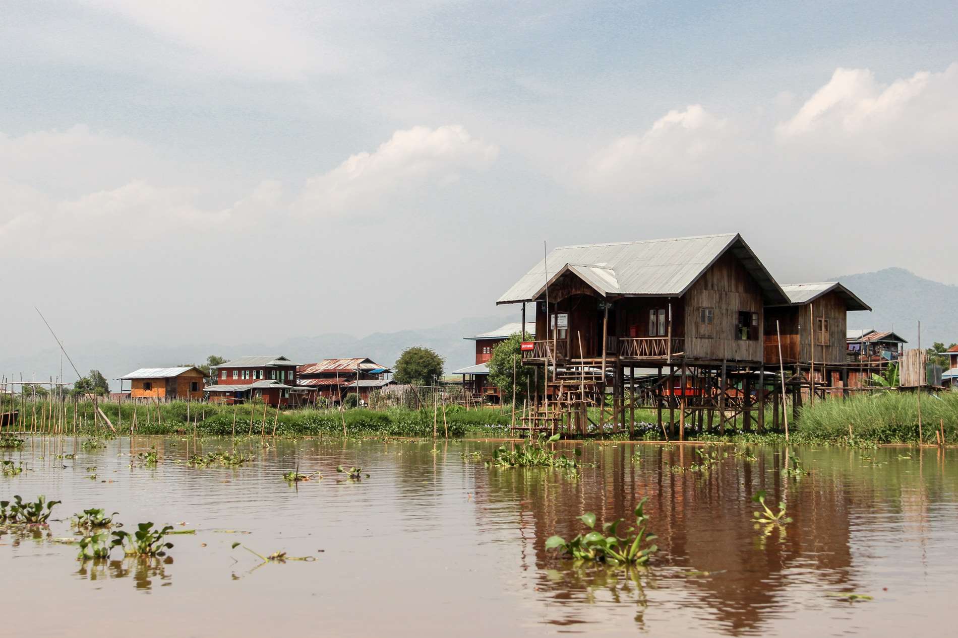 Large wooden stilt houses on a large green floating island on Inle Lake in Myanmar. 
