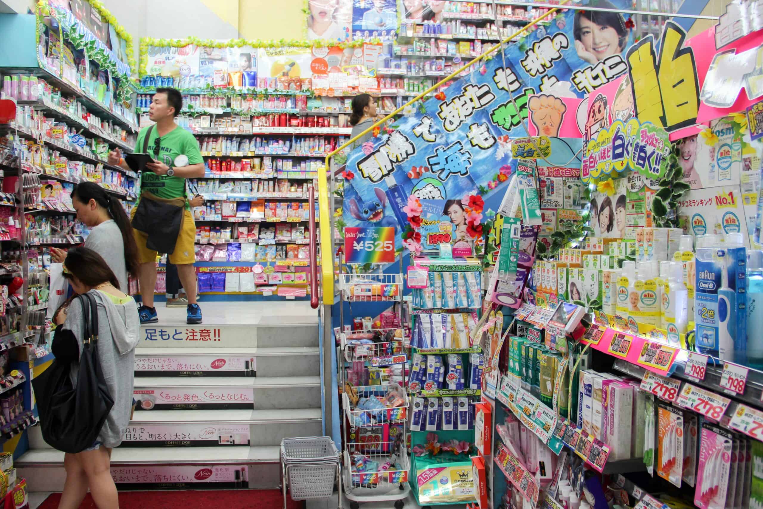 Three people browsing the full stocked shelves of a beauty store in Tokyo, Japan.