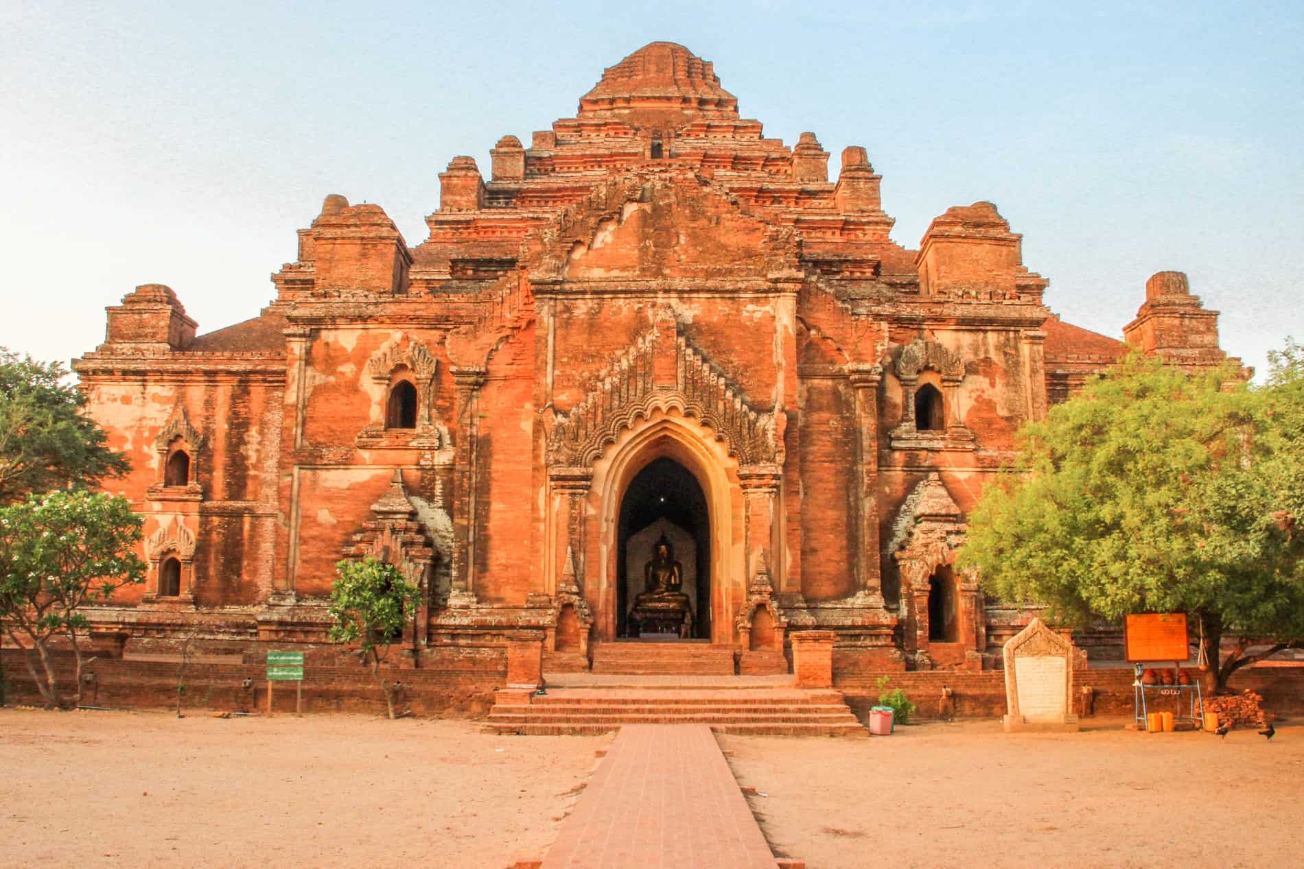 A golden buddha sits in the doorway of the large orange stone Dhammayangyi Temple in Bagan. 