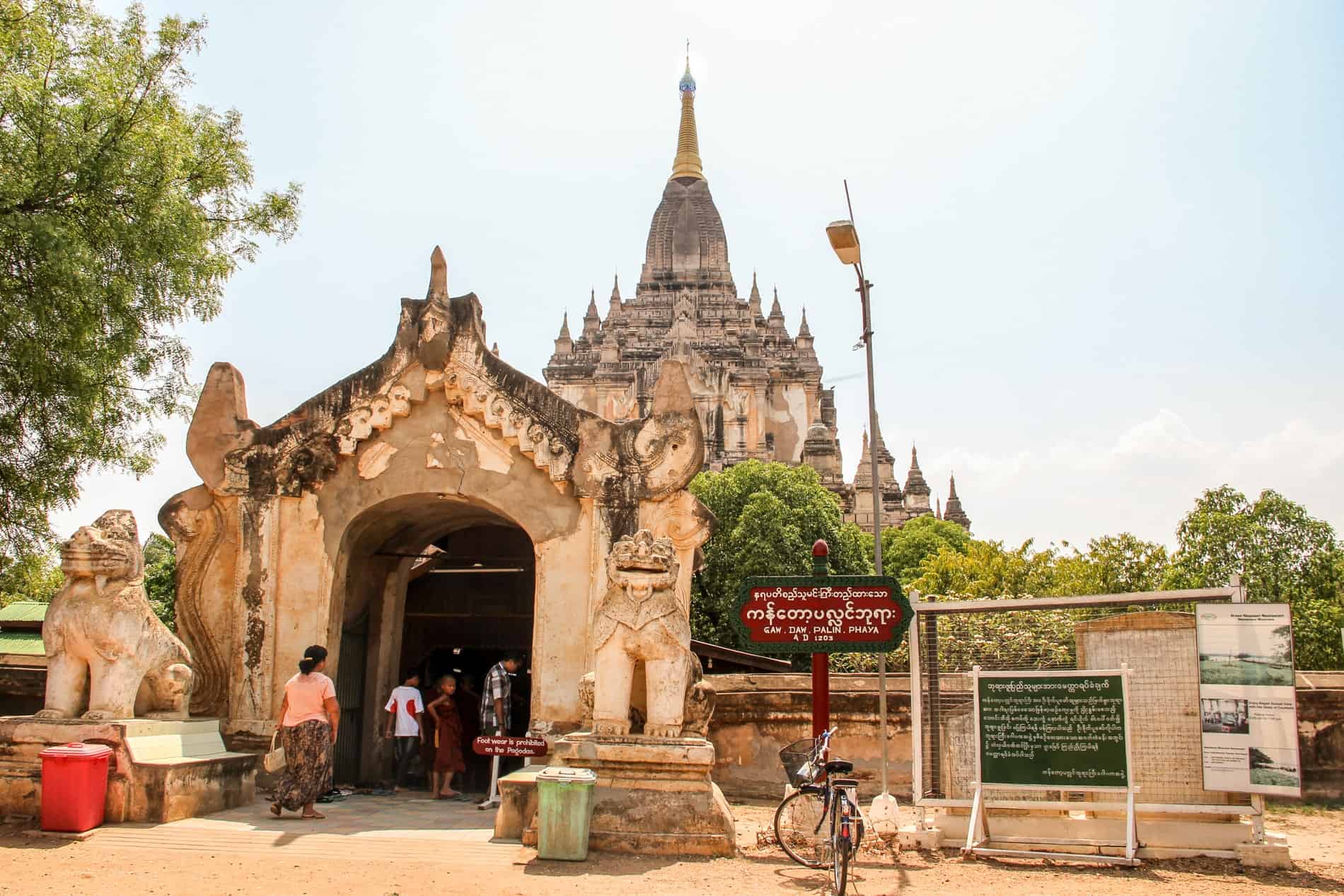 People enter the lion figure decorated stone gate of the Gawdawpalin Temple in Bagan. 