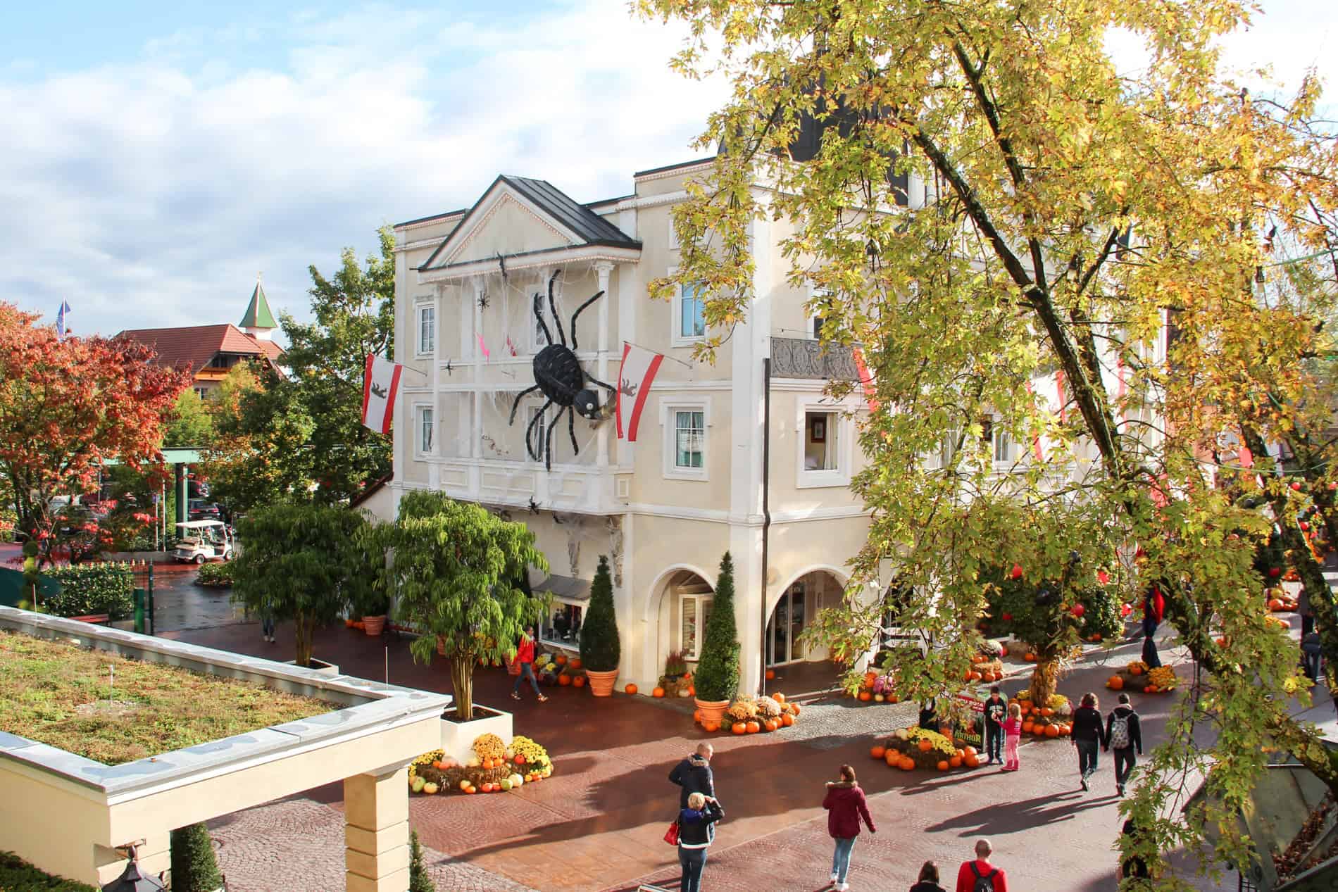 A giant black spider Halloween decoration mounted on the front of a large white building.