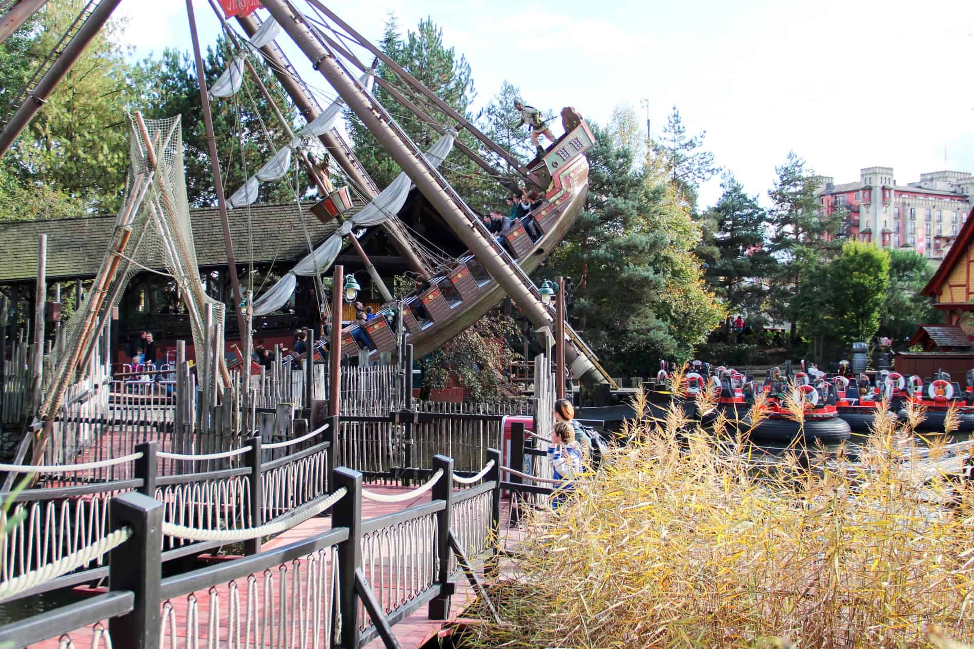 A large brown brown boat swings above a seated ride at the Europa Park amusement park. 