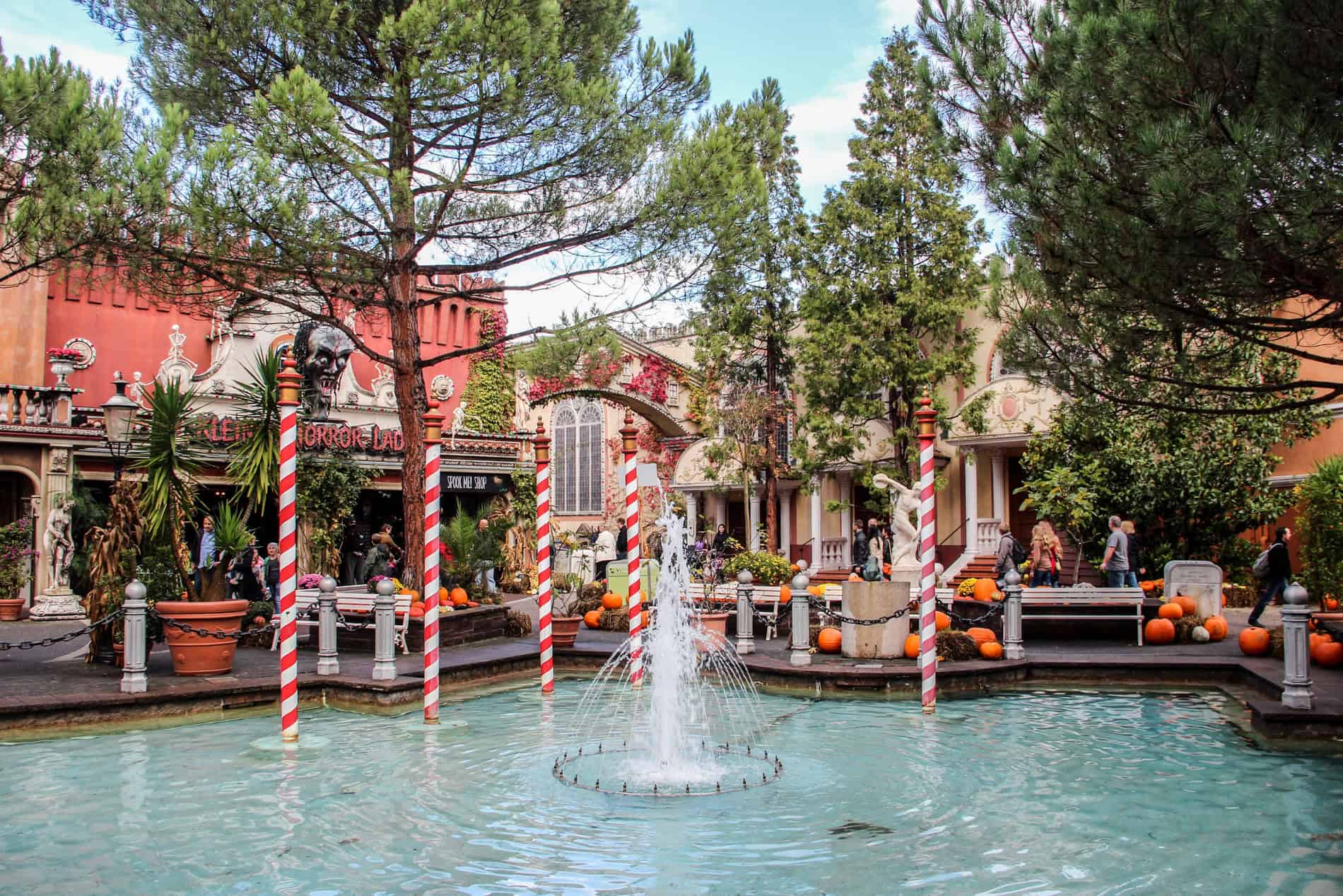 A replica of the waters of Venice with red and white boat poles, in front of a row of stores in the themed Europa Park. 