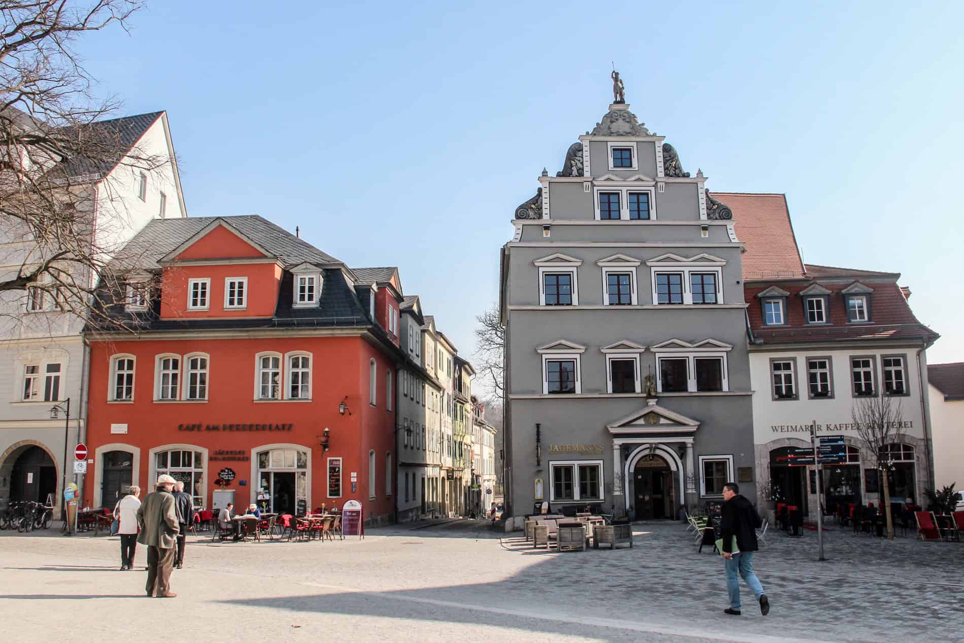 An orange house and grey burgher house in Weimar's historic cobblestoned centre. 