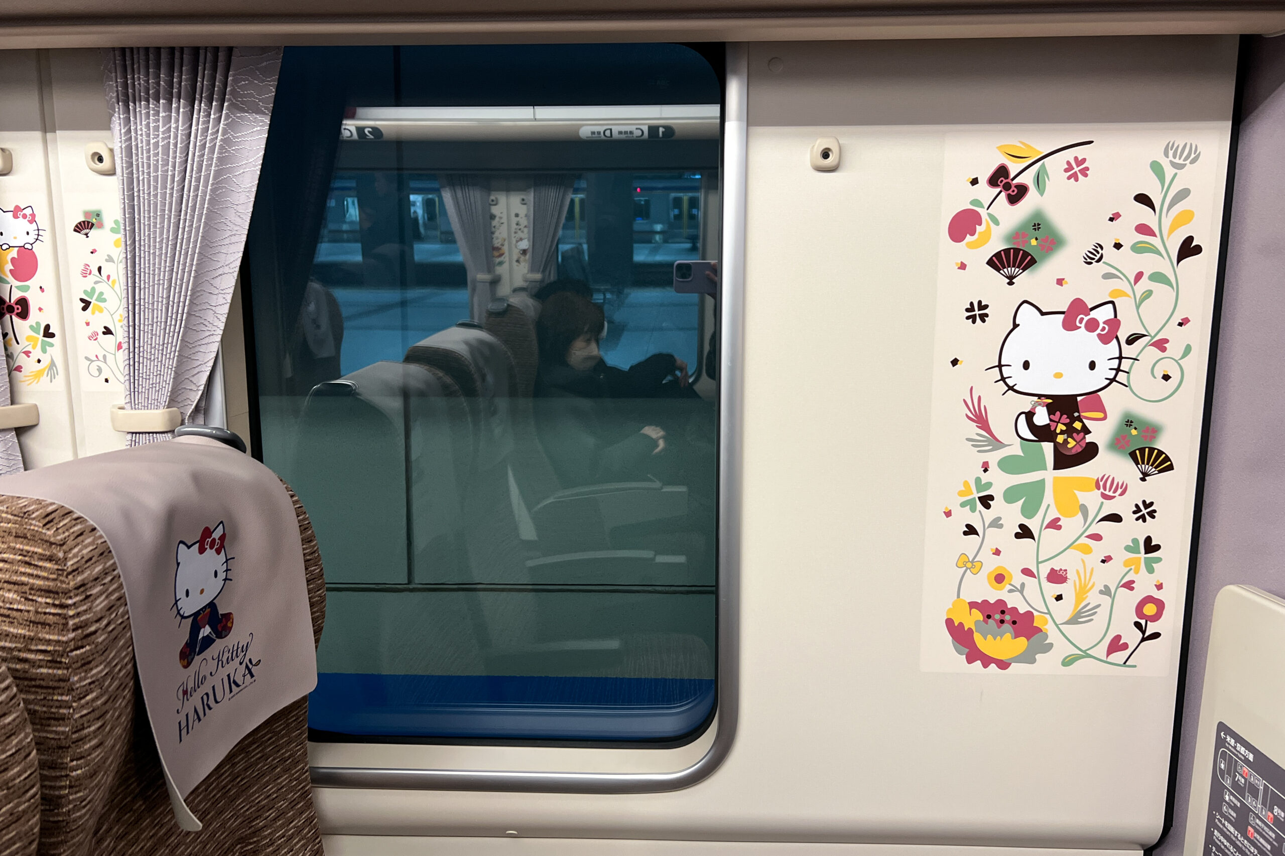 Interior Hello Kitty decorative details of the HARUKA train carriage, including character prints on seat covers and patterned motifs on car walls.
