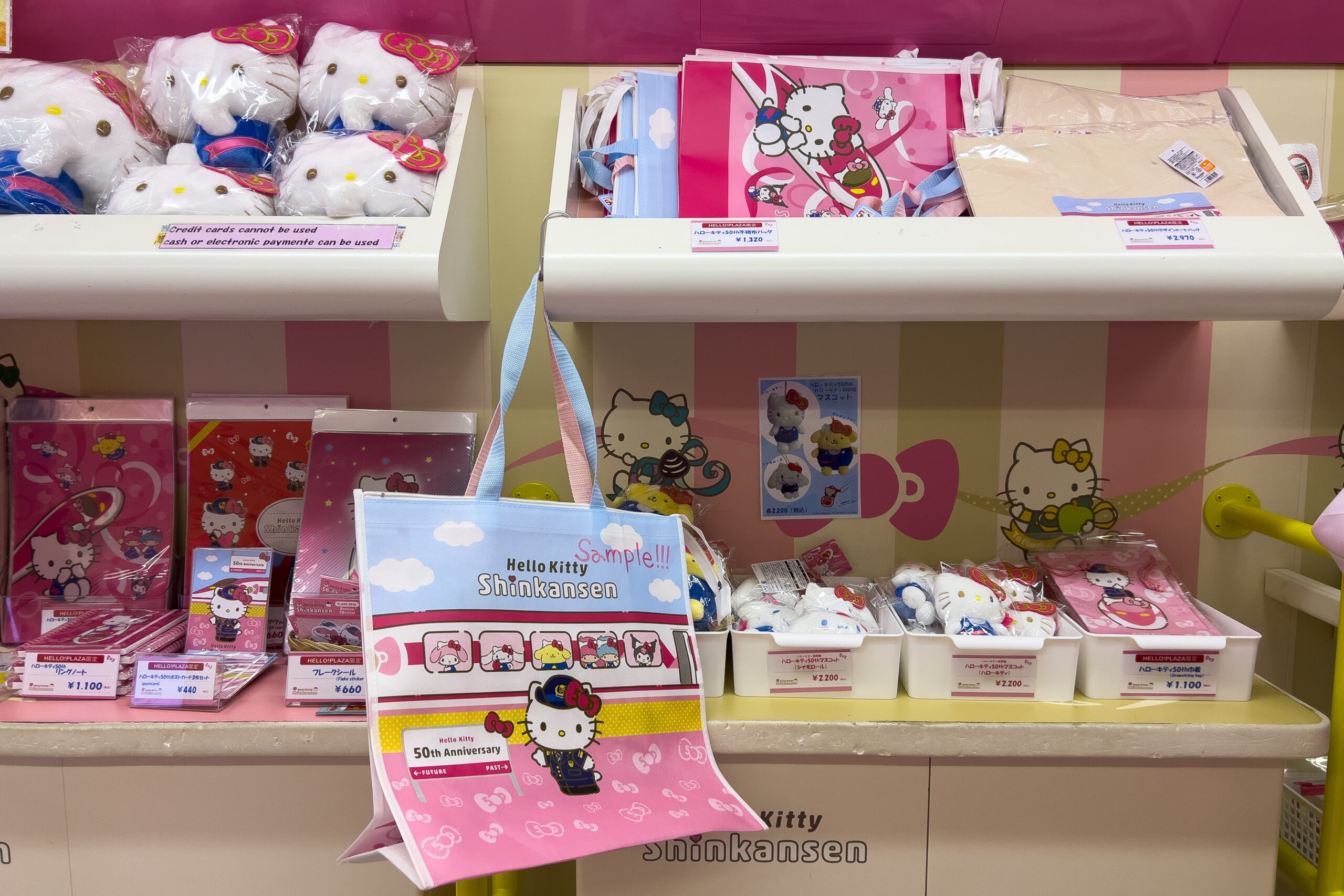 Close up of Hello Kitty Shinkansen merchandise including bags, plush toys, notebooks and folders.