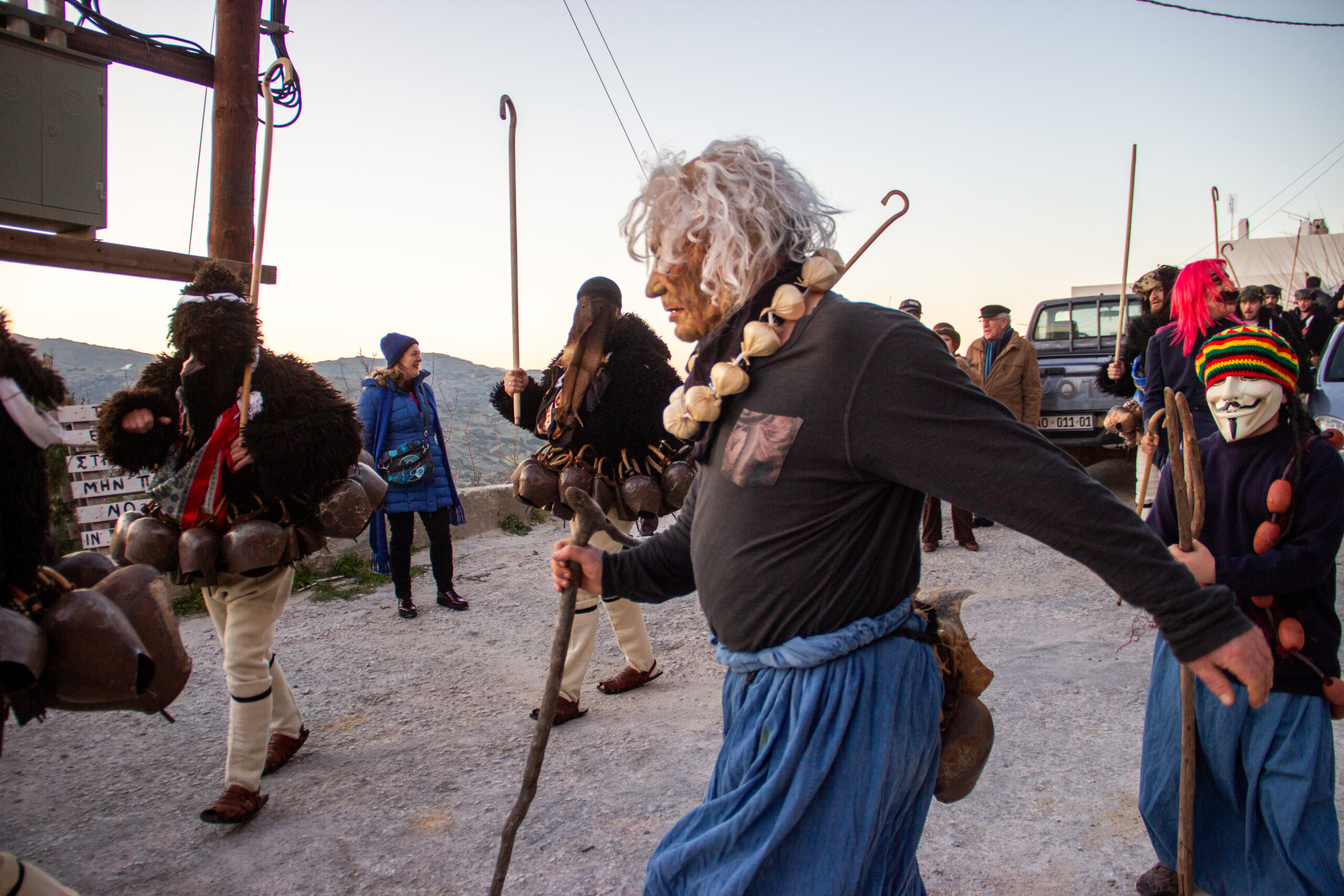 Masked characters at the Skyros Carnival with spectators visible in the background.