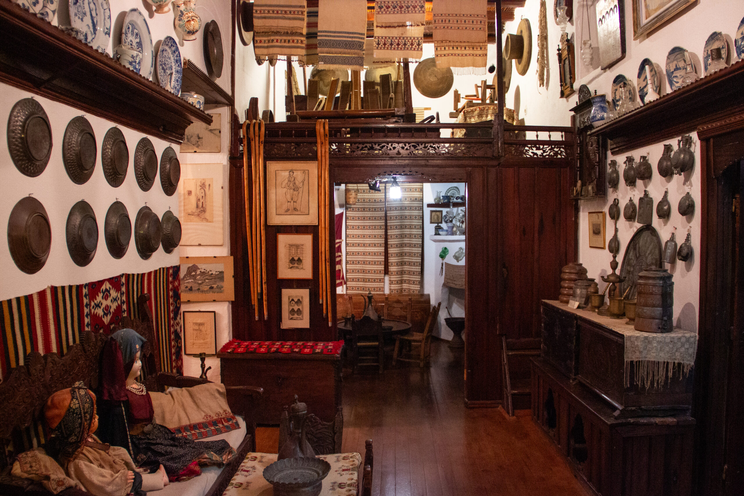 Interior of the Skyros Faltaits Museum filled floor to ceiling with fabrics, ceramics, pictures and metalware.