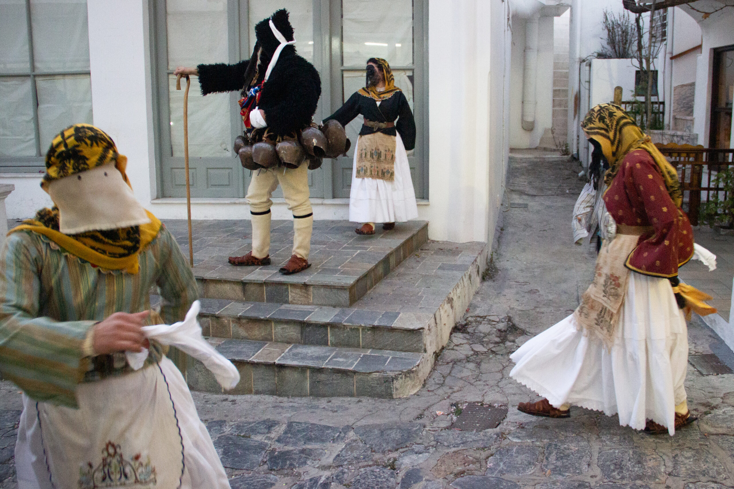 Four masked Skyros Carnival figures in traditional clothing parading in the town's white-washed streets.