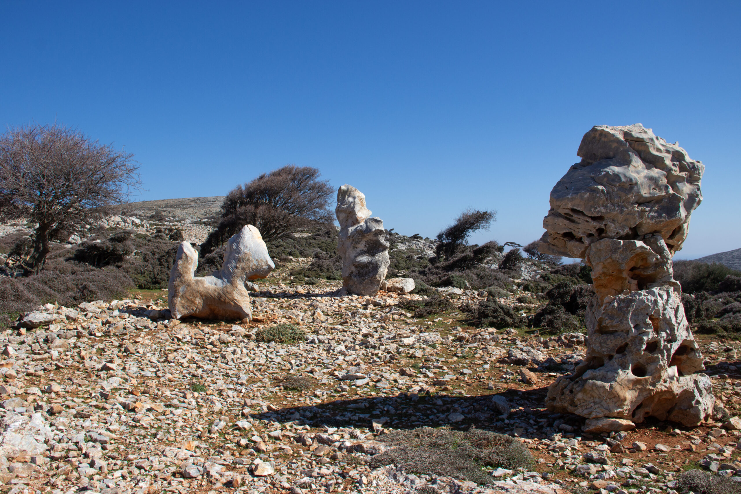 Three unique limestone formations – the first resembling a pony – on an arid, rocky landscape in Skyros.
