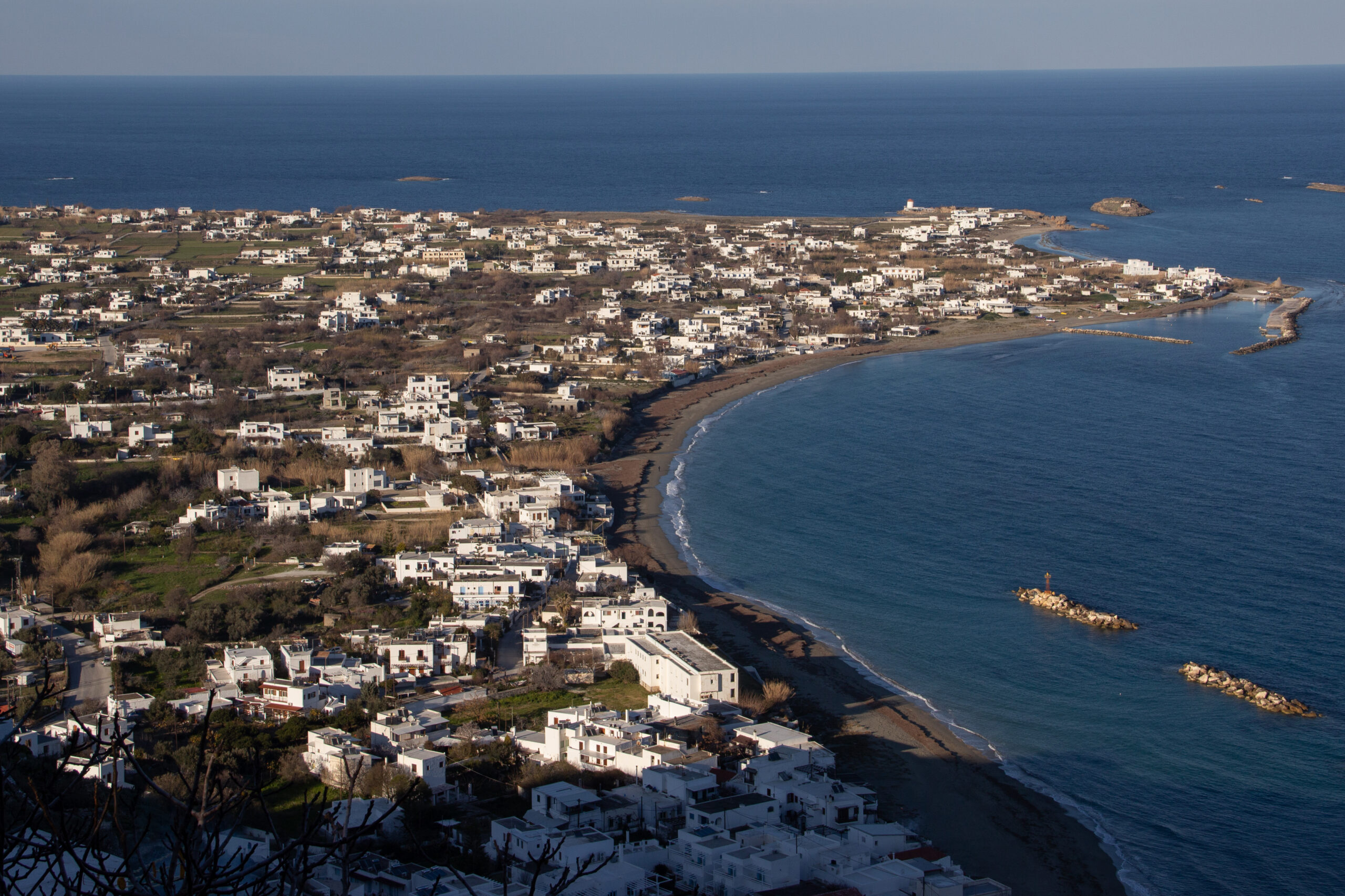 Elevated view over a dark sandy bay covered with white houses on Skyros Island, Greece.